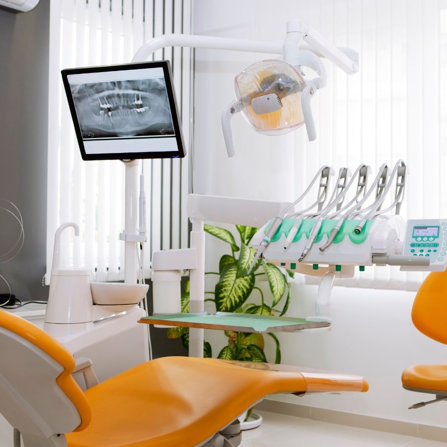 A dentist's clinic with a chair, x-ray screen, and various tools