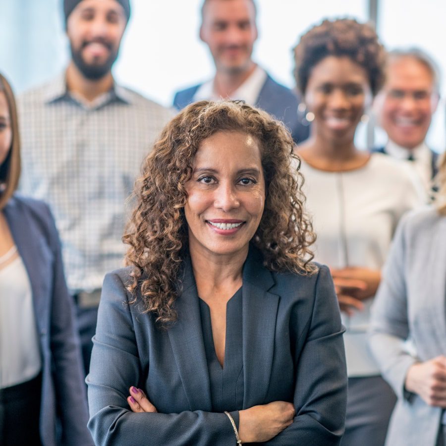 A group of business professionals smile for the picture, one woman is highlighted in the foreground