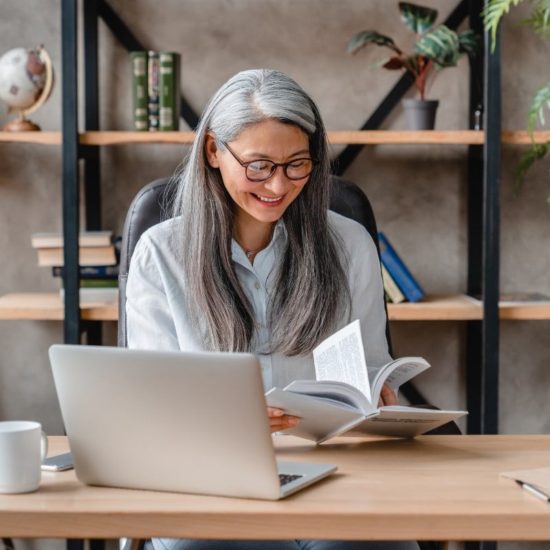 A woman flips through the pages of a book while sitting in her office